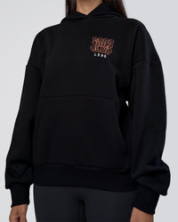 Woman wearing GTC CVC Fleece Unisex Oversized Hoodie - Black-Cantaloupe | Model:Rhiley | Size:XS