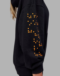 Woman wearing Hyped Unisex Oversized Hoodie - Black-Vibrant Orange | Model:Neve | Size:XS