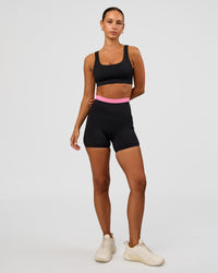 Woman wearing Liberate High-Rise 4" Short Pockets - Black-Candy Pink | Model:Brylee | Size:XS