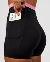 Woman wearing Liberate High-Rise 4" Short Pockets - Black-Candy Pink | Model:Brylee | Size:XS