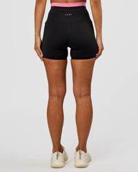 Woman wearing Liberate High-Rise 4" Short Pockets - Black-Candy Pink | Model:Brylee | Size:XS