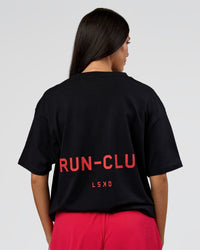 Woman wearing RUN CLUB FLXCotton Tee Oversize - Black-Scarlet | Model:Rhiley | Size:XS