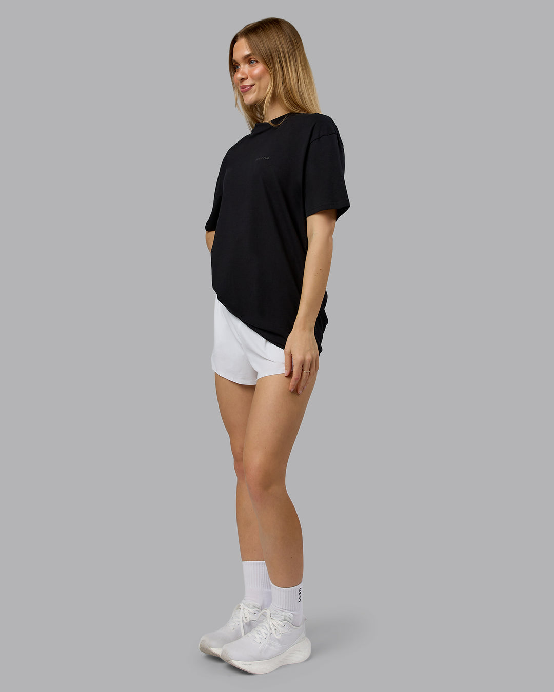 Woman wearing RUN CLUB FLXCotton Tee Oversize - Black-Reflective | Model:Emilie | Size:XS