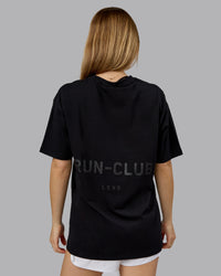 Woman wearing RUN CLUB FLXCotton Tee Oversize - Black-Reflective | Model:Emilie | Size:XS