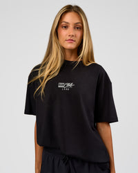 Woman wearing Run Club Script FLXCotton Oversized Tee - Black-Alloy | Model:Georgia | Size:XS