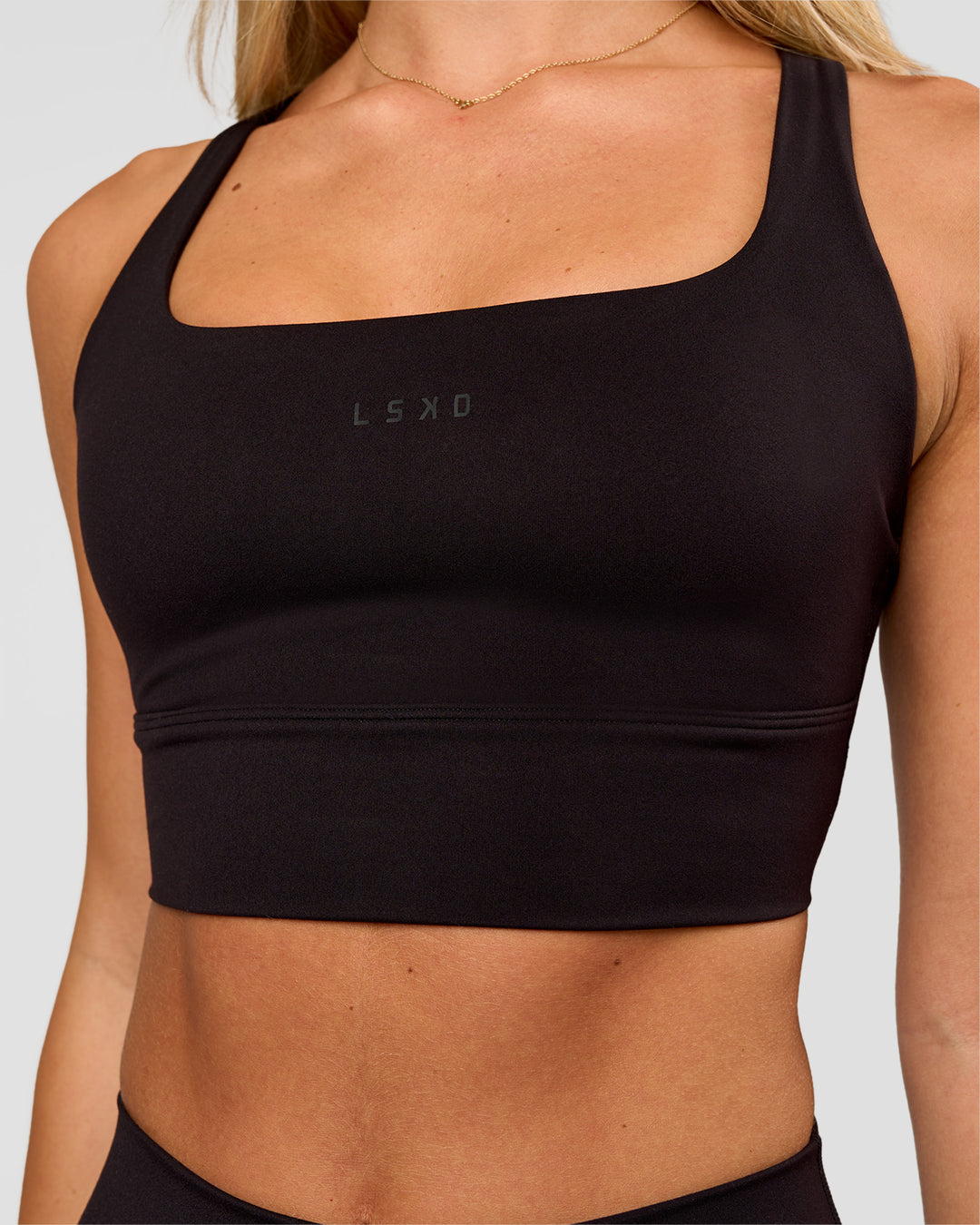 Woman wearing Twist Long Line Sports Bra in Black | Model:Issy | Size:XS