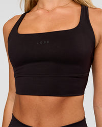 Woman wearing Twist Long Line Sports Bra in Black | Model:Issy | Size:XS