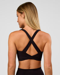 Woman wearing Twist Long Line Sports Bra in Black | Model:Issy | Size:XS