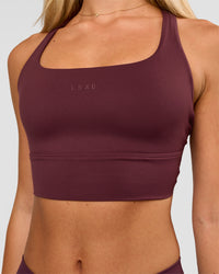 Woman wearing Twist Long Line Sports Bra in Cherry Lacquer | Model:Issy | Size:XS