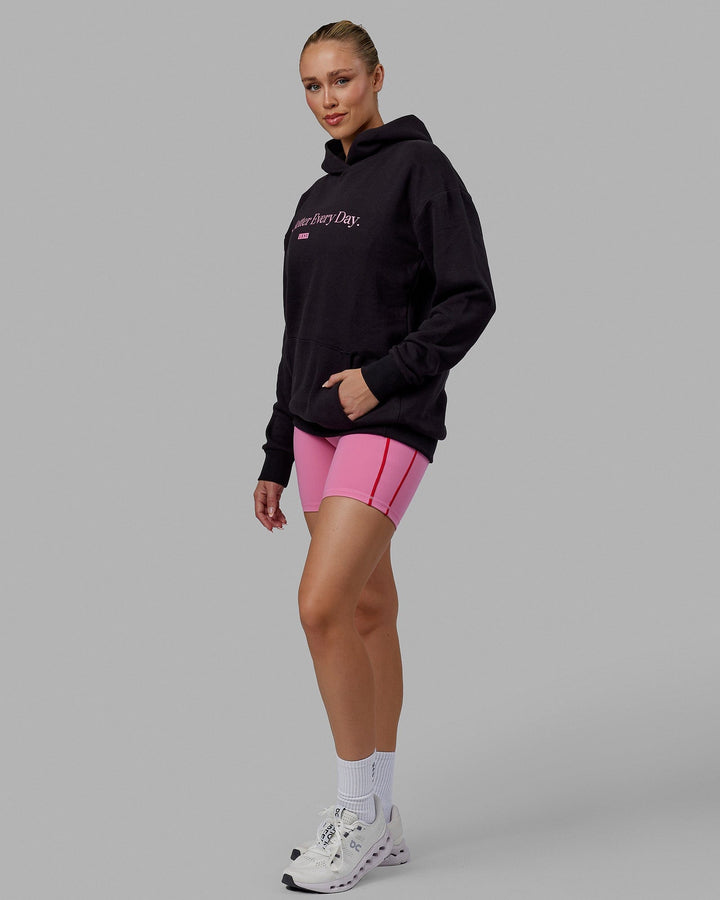 Woman wearing Unisex 1% Better Hoodie Oversize - Black-Pink Rose