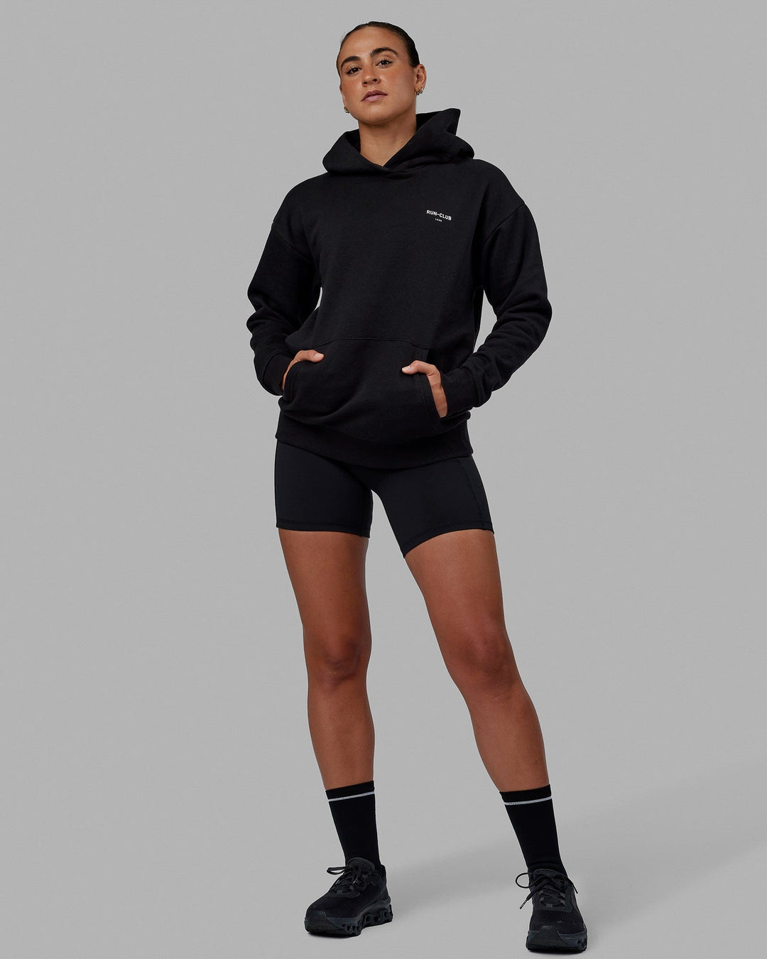 Woman wearing Unisex RUN-CLUB Hoodie Oversize - Black