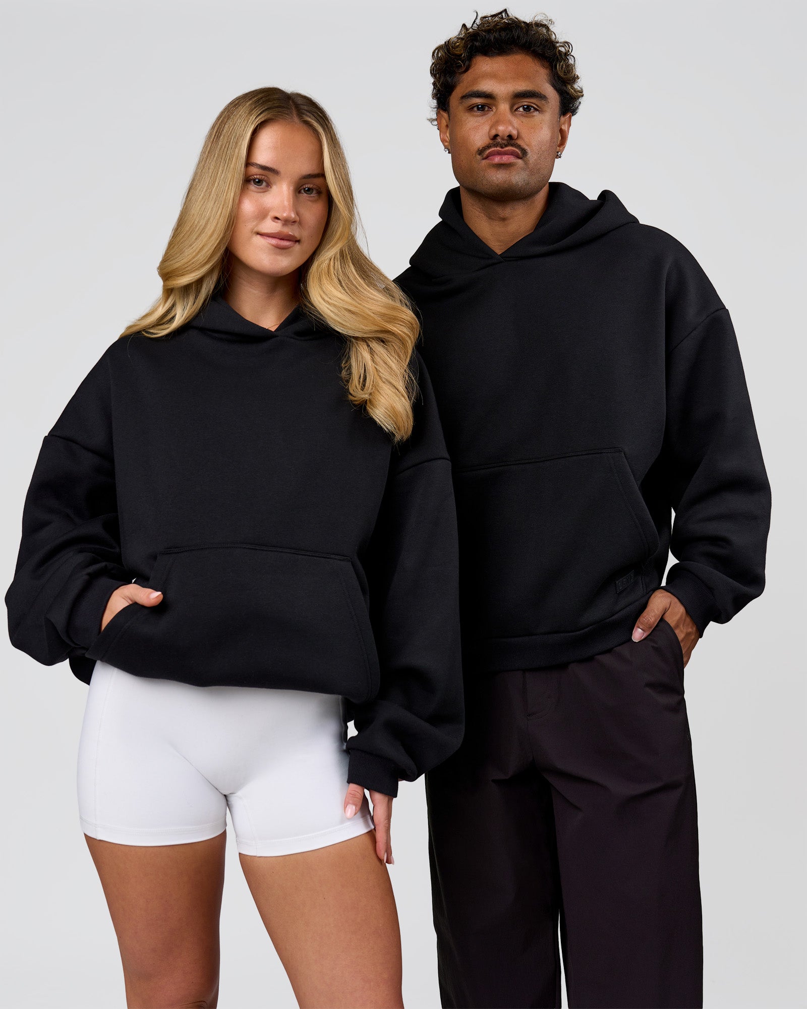 Duo wearing Tonal Legacy Boxy Hoodie - Black-Black | Model:Issy | Size:XS | Model:Xav | Size:L