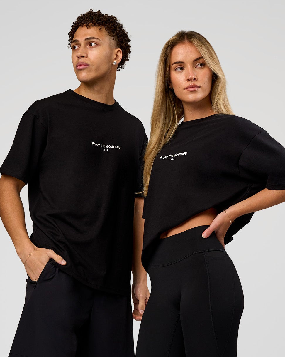 Duo wearing VS1 Enjoy The Journey FLXCotton Oversize Tee - Black | Model:Issy | Size:XS | Model:Leandro | Size:M