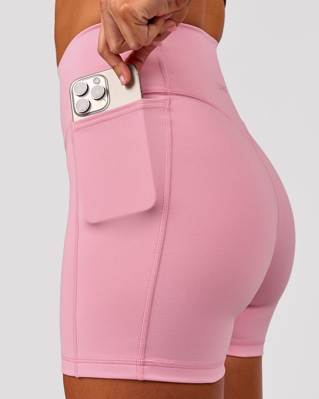 Woman wearing Fusion V-Contour Ultra High-Rise 4" Short Pockets - Pink Rose | Model:Charli | Size:XS - view 1