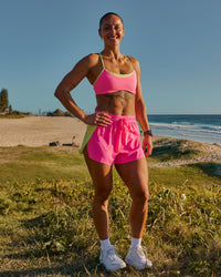 Woman wearing Accelerate 3" High-Rise Running Short - Lime Glo-Sugar Plum | Model:Chelsea | Size:XS | Thumbnail Index: 1