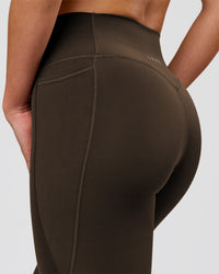 Woman wearing Fusion V-Contour High-Rise Flared Petite Legging Pockets - Ground Coffee | Model:Issy | Size:XS | Thumbnail Index: 5