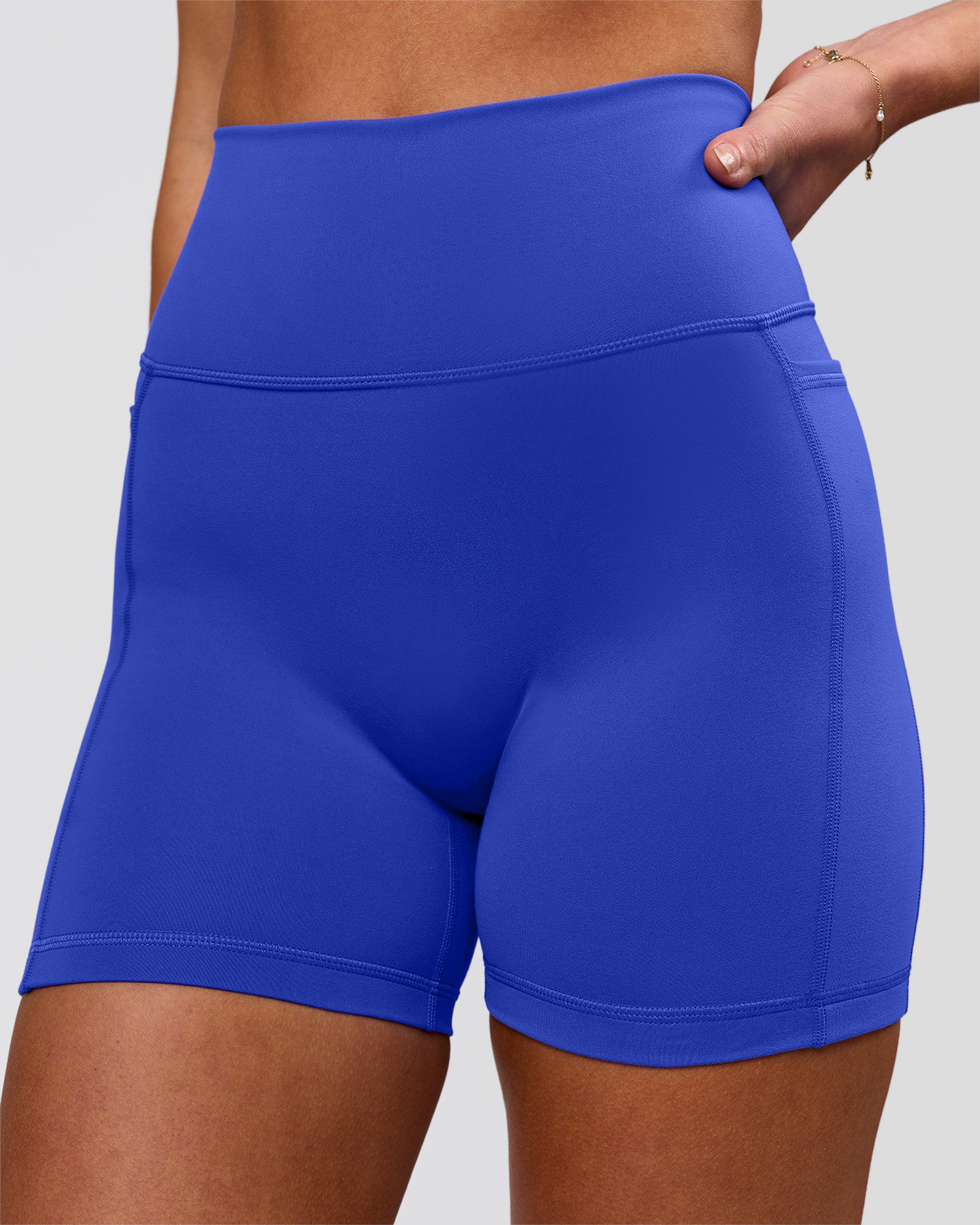 Woman wearing Fusion V-Contour Ultra High-Rise 4" Short Pockets - Power Cobalt | Model:Issy | Size:XS