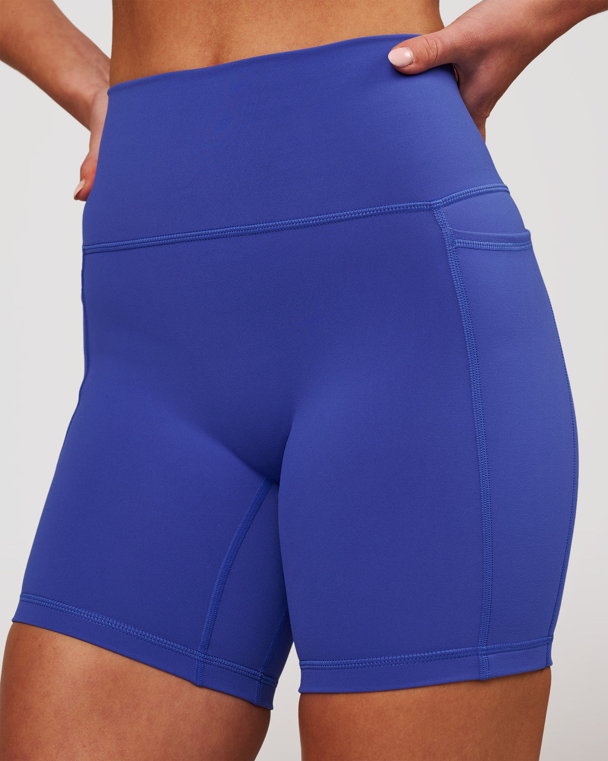 Woman wearing Fusion V-Contour Ultra High-Rise 6" Short Pockets - Power Cobalt | Model:Issy | Size:XS
