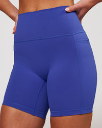 Woman wearing Fusion V-Contour Ultra High-Rise 6" Short Pockets - Power Cobalt | Model:Issy | Size:XS | Thumbnail Index: 1