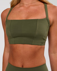 Woman wearing Momentum Corset Sports Bra - Pure Olive | Model:Issy | Size:XS | Thumbnail Index: 0