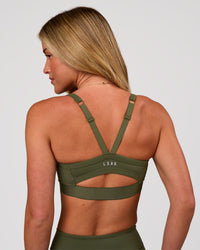 Woman wearing Momentum Corset Sports Bra - Pure Olive | Model:Issy | Size:XS | Thumbnail Index: 1